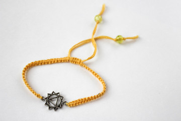 yellow braded bracelet with chakra (manipura) on white background