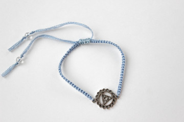 Fototapeta na wymiar blue braded bracelet with chakra (vishuddha) on white background