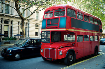 Traditional red double-decker Routemaster bus, introduced in 1956, making its way along an empty street in London, UK