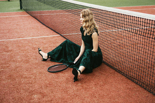 Luxury glamour fashion woman on tennis court holding racket and posing like model
