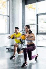 sportsman and sportswoman doing lunges with balls in sports center