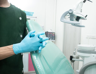 Male dentist in green uniform wear blue rubber gloves.