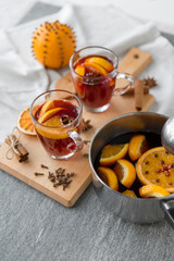 christmas and seasonal drinks concept - pot with hot mulled wine, orange slices, aromatic spices and ladle on grey background