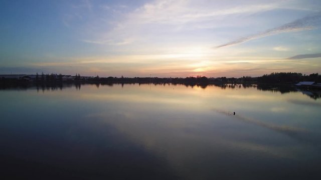 Vdo. Aerial view evening above reservoir around with green tree and yellow sun ling in cloudy sky background, sunset at Krajub reservoir, Nong Kob, Ban Pong, Ratchaburi, Thailand.