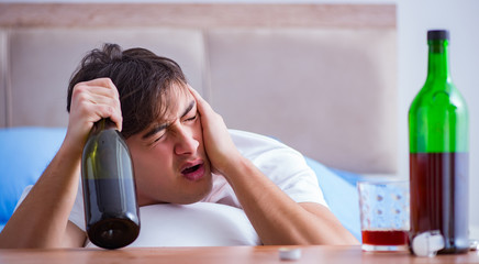 Man alcoholic drinking in bed going through break up depression