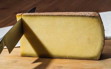 Knife cutting a piece of Comte a famous French cheese