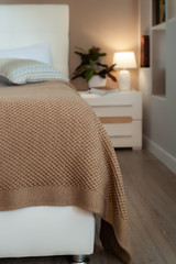 beige knitted blanket on bed in cozy bedroom