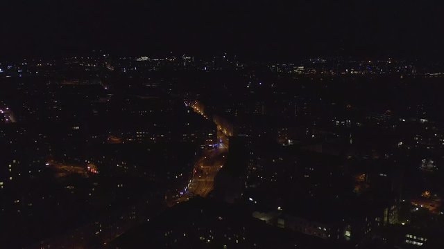 Aerial, tracking, drone shot, panning over the Runeberginkatu avenue and the Toolo cityscape, in downtown Helsinki, on a dark, autumn night, in Uusimaa, Finland