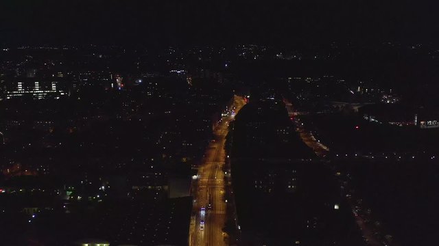 Aerial, drone shot, over the Mannerheimintie avenue in Toolo, towards the tram station, in downtown Helsinki, on a dark, autumn night, in Uusimaa, Finland