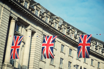 Obraz na płótnie Canvas Union Jack flag decorations strung above the streets of London, UK under soft blue sky