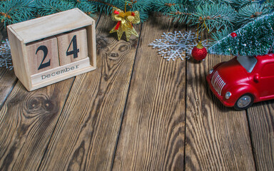 Christmas Eve Date On Calendar, December 24, with Christmas decorations and festive lights on fir twigs, frosted red berries and wooden hearts on green background