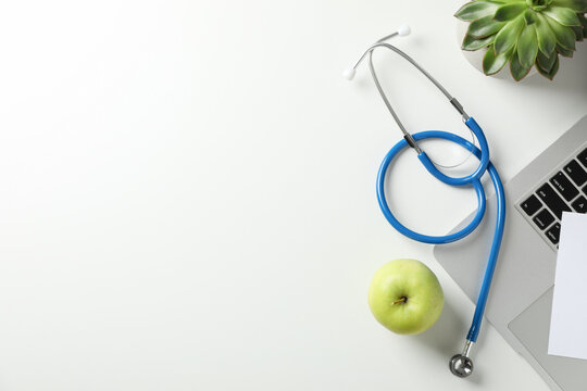 Stethoscope, Apple, Laptop And Plant On White Background, Top View. Doctor Workplace