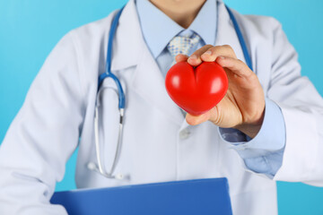 Doctor with stethoscope and heart against blue background, close up