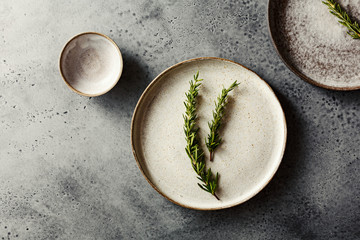 Flat ceramic plates. Beautiful table setting with rosemary sprigs.