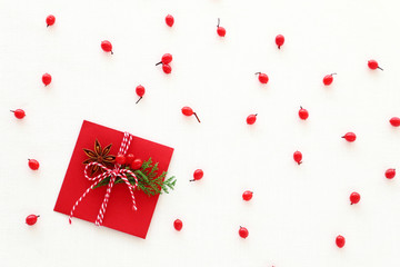 Christmas gift with red berries, star anise, evergreen twig.Red envelope.Flat lay, top view, copy space