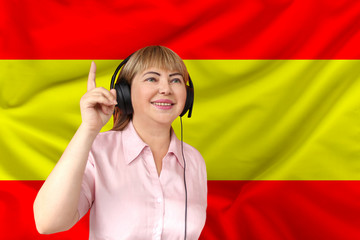 woman in headphones against the background of the national flag of Spain on delicate shiny silk,...