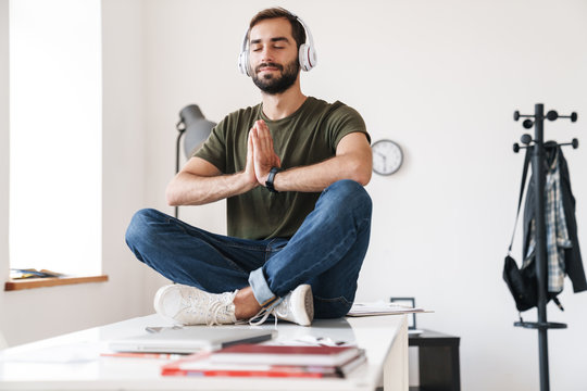 Image of calm man listening music with headphones while sitting on desk
