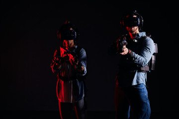 Naklejka premium Youg couple direct their virtual weapons at camera, in search of enemy, virtual war. Futuristic, fantasy, innovation concept