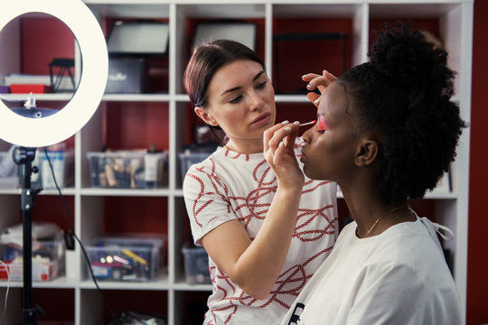 Make up artist doing makeup for african fashion model in studio