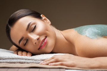 Obraz na płótnie Canvas wellness, beauty and cosmetology concept - beautiful young woman lying with blue clay mask at spa