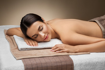 Obraz premium wellness, beauty and relaxation concept - young woman lying at spa or massage parlor
