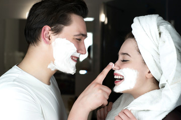 funny couple handsome man applying jokingly foam on beautiful woman's nose having fun both with...