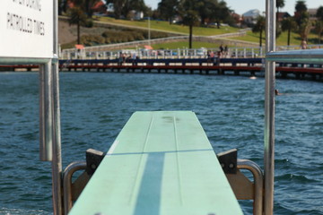 blue diving board pocking out over the waves in a bay and protected sea bath in Geelong, coastal Victoria