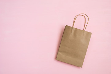 Empty brown paper bag with handles for shopping on a pink background. Flat lay. Copy space.