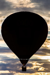 Silhouette of a hot air balloon flying at sunset.