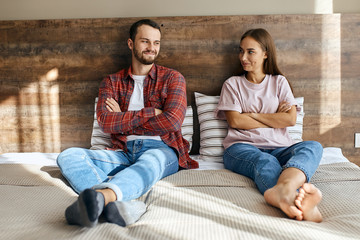 Lovely happy family sitting in bedroom, can not hide smile, ready to make up quarrel, looking at each others, waiting for partner to start talking, optimistic mood, portrait