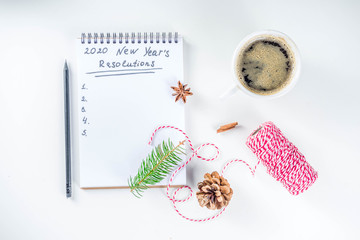 New year Resolution Concept - 2020 number and text in notepad. Coffee cup, Christmas decoration and pen for writing, White background copy space