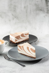 Delicious homemade chocolate cake with cottage cheese Zebra Marble cake . Tasty breakfast. Piece of cake on grey plate, white cup on white marble background. Selective focus. Vertical photo.