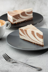 Delicious homemade chocolate cake with cottage cheese Zebra Marble cake . Tasty breakfast. Piece of cake on grey plate, white cup on white marble background. Selective focus. Vertical photo.