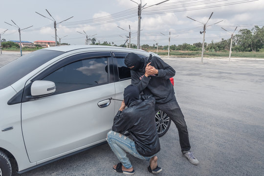 Two robber thief Criminal Bandits in Robes Standing Next gun robbed and forced open the car door. To seize the property of the Victim.Thief Concept Photo.