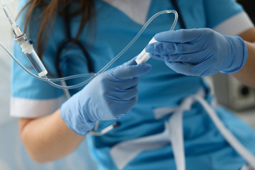 Female nurse hand in blue protective gloves hold dropper