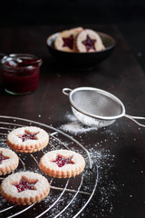 Weihnachtskekse backen auf einem braunen Holztisch mit Marmelade und Puderzucker, rustikaler Stil