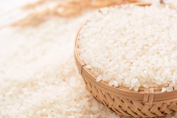 Raw white polished milled edible rice crop on white background in brown bowl, organic agriculture design concept. Staple food of Asia, close up.