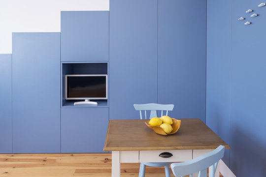 Minimal interior design kitchen in small apartment. Blue walls, yellow lemons on little table