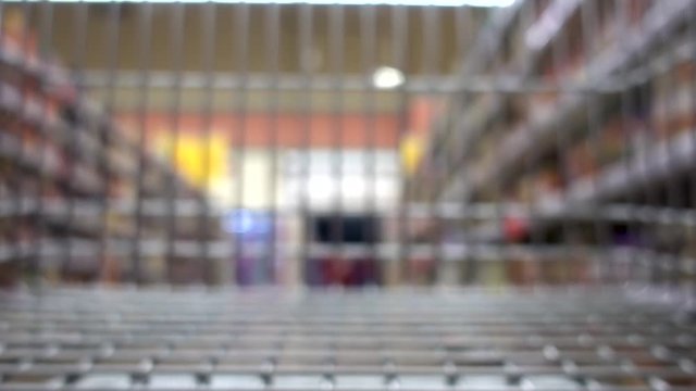 Shopping cart moving through supermarket. Purchase of products. Blurred background.