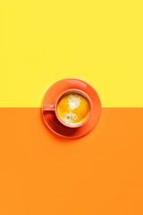One cup of coffee on two-toned background.