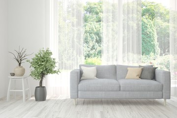 Stylish room in white color with sofa and summer landscape in window. Scandinavian interior design. 3D illustration