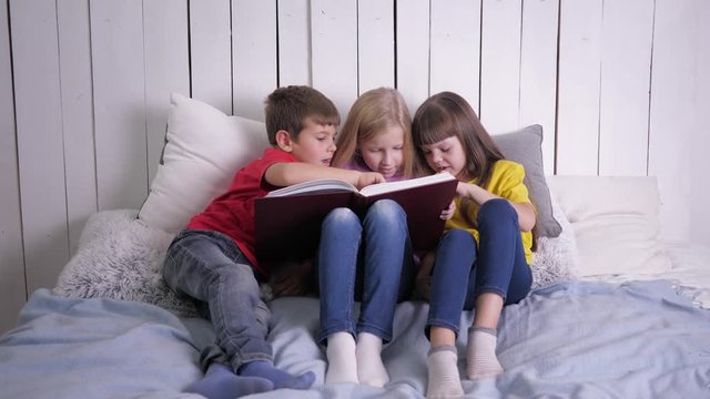 education, smart kids in multicolor clothes learn to read at home sitting on the couch