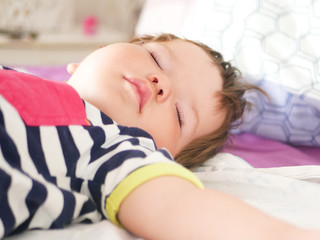 Obraz na płótnie Canvas Childrens daytime sleep. Funny baby sleeping on the back of the bed at home. Children's day position. Healthy sleep. Arms outstretched during sleep
