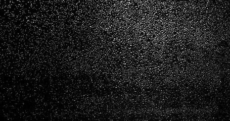 Drops of rain trickling down on black background.