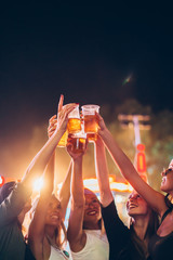 Group of female friends cheering with beer in amusement park - obrazy, fototapety, plakaty