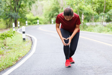 Woman running hurt at her knee between run training.