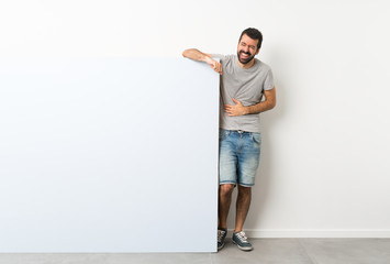 Young handsome man with beard holding a big blue empty placard smiling a lot