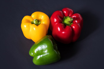 Fresh vegetables Three sweet Peppers on darck background.