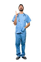 Full-length shot of Surgeon doctor man pointing up and surprised over isolated white background