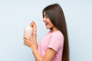 Young woman with strawberry milkshake over isolated blue background